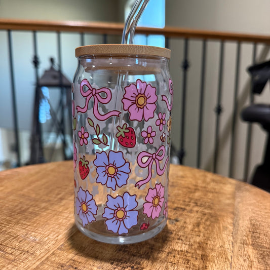 Glass tumbler with floral designs and a straw on a wooden table