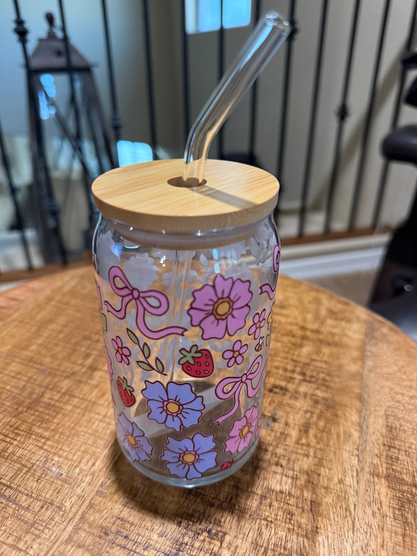 Tumbler with floral design and wooden lid on a wooden surface